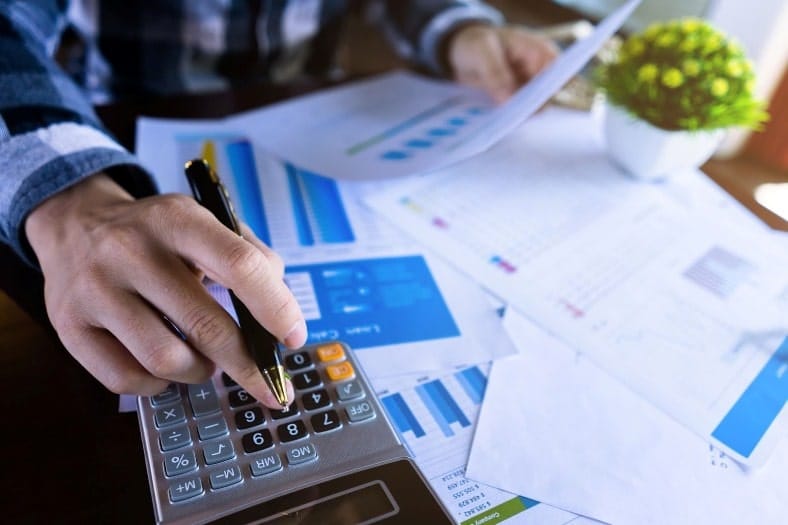 a person managing their bills. Man with pen in hand using calculator