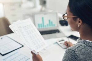 woman looking at a paper bill and typing numbers into a calculator