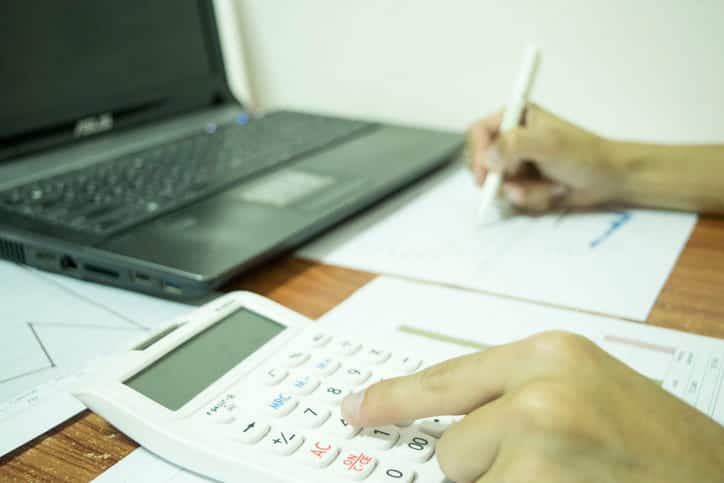 person using a calculator to figure out their debt before declaring bankruptcy.