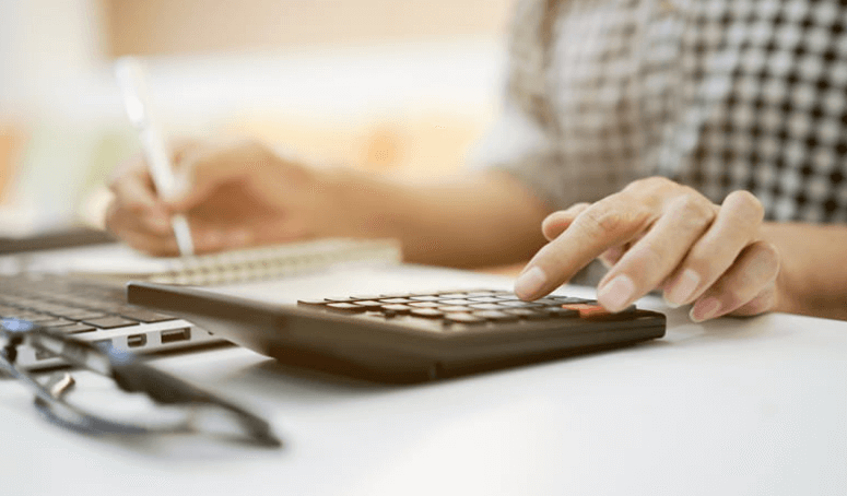 a persons hand using a calculator as they write out their debts filing for bankruptcy