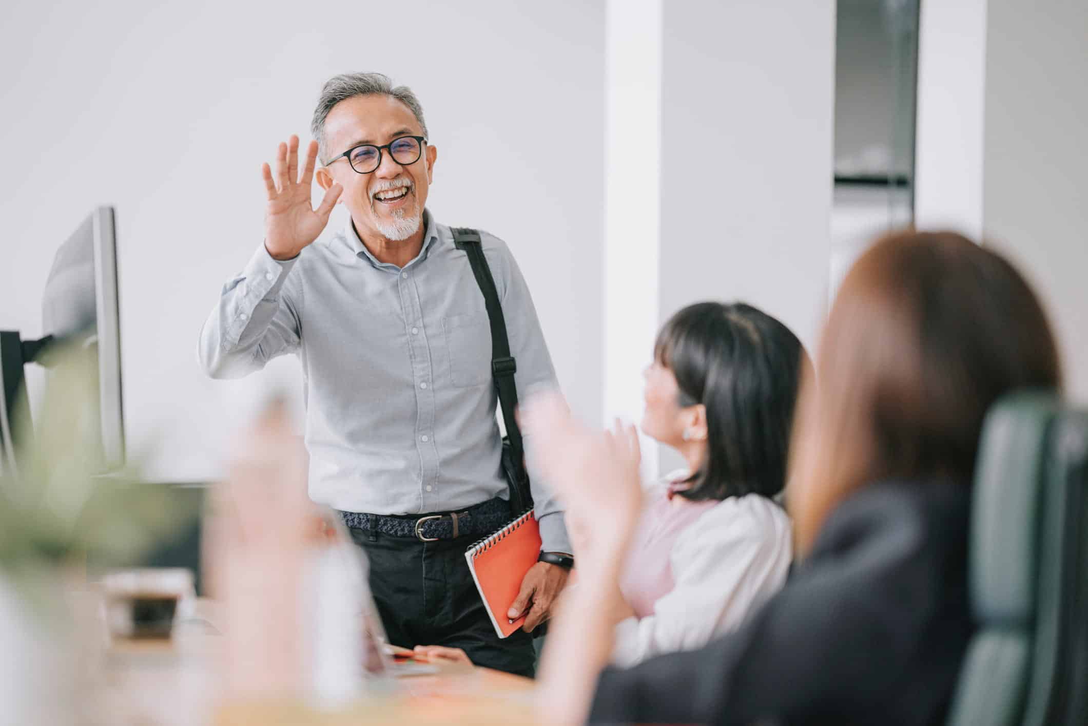 elderly part-time worker waving at his co-workers