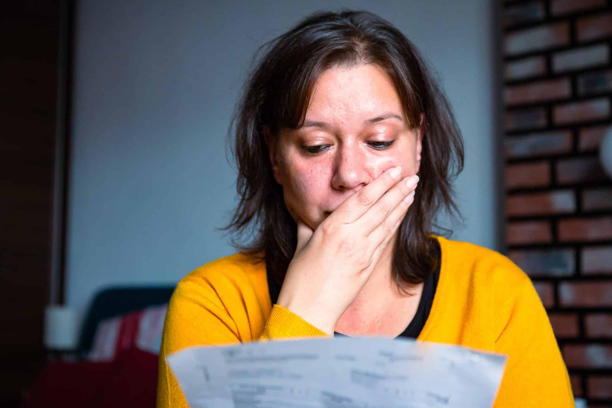 Worried woman checking bills at home