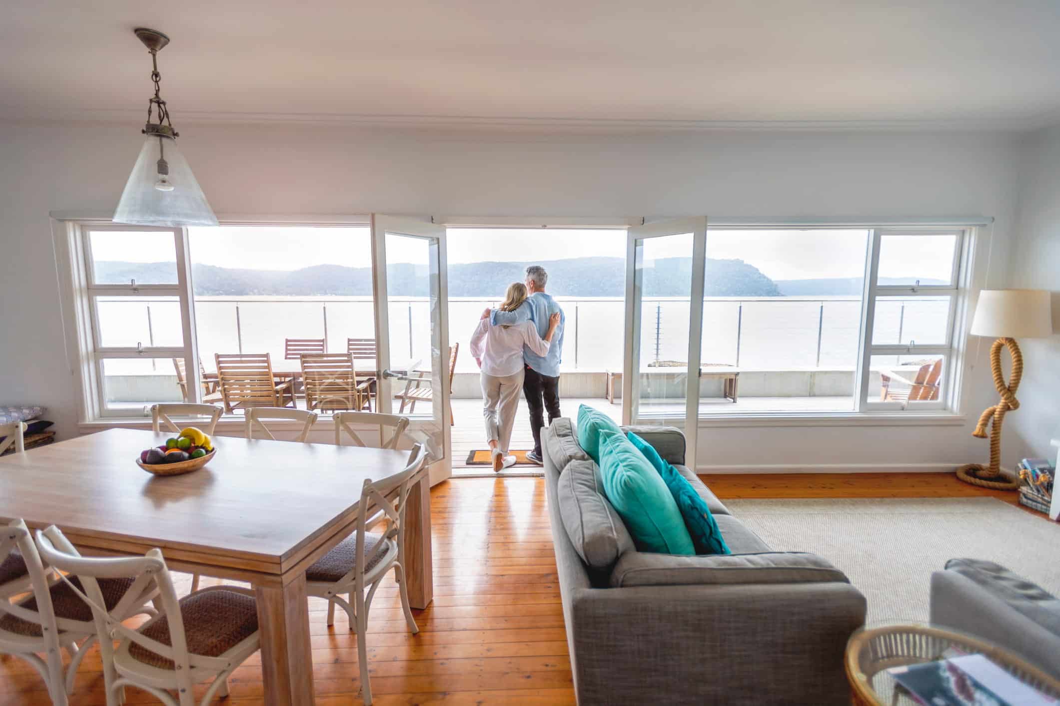 retired couple hugging each other and staring at a view of water and mountains.