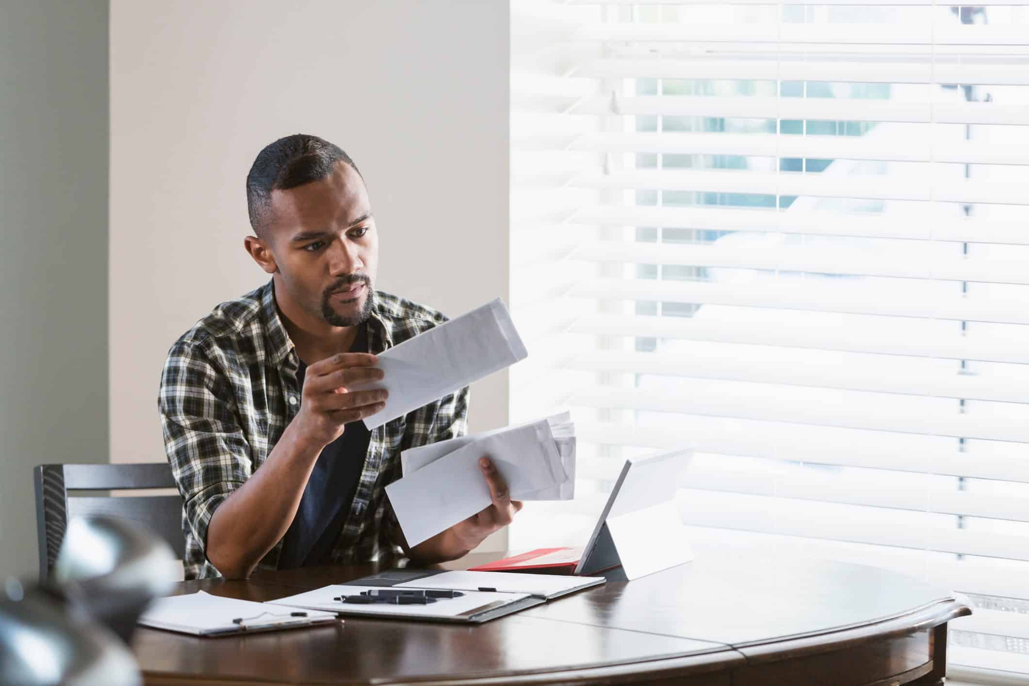 man looking at debt notice from debt collectors