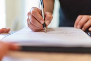 hand of woman holding pen and signing documents