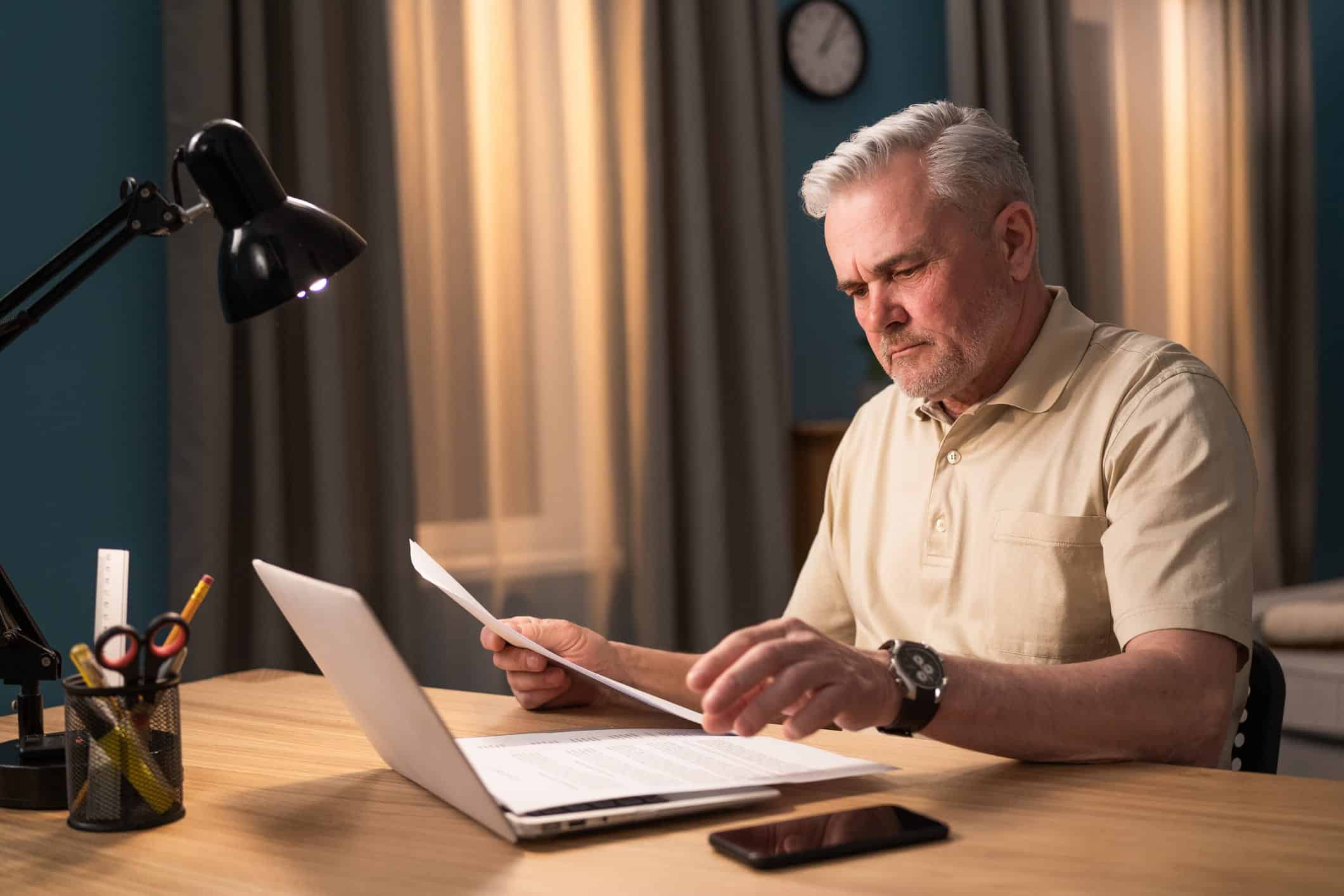 man filing for bankruptcy on a laptop computer while holding a document