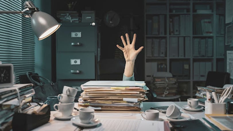 person overwhelmed with huge pile of paperwork for bankruptcy