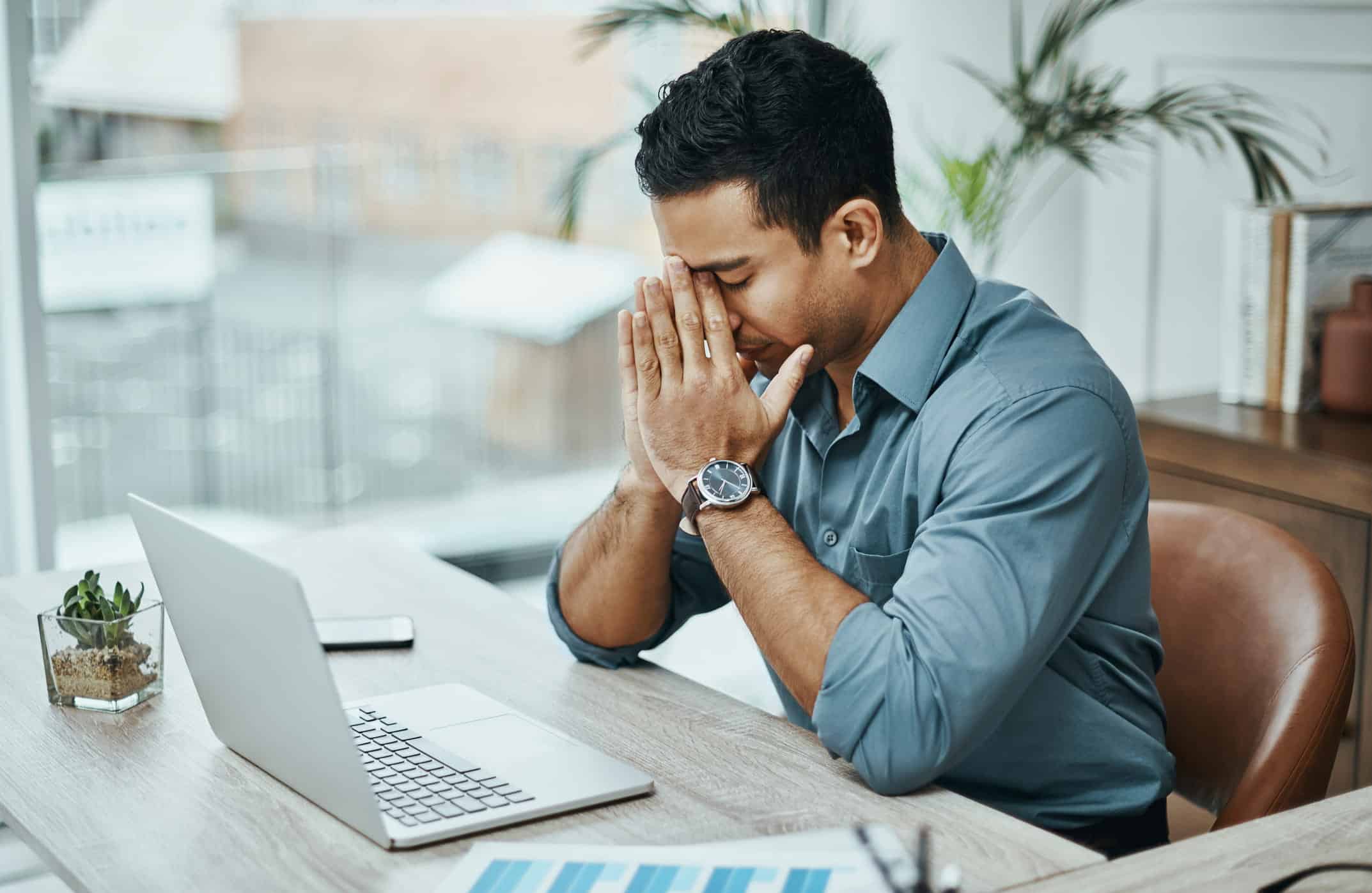 stressed man who is in debt with his hands on his face