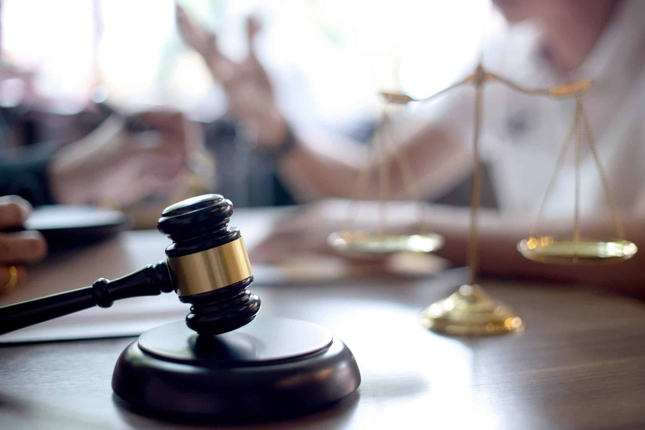 gavel of justice on a desk and lawyer and client in the background talking