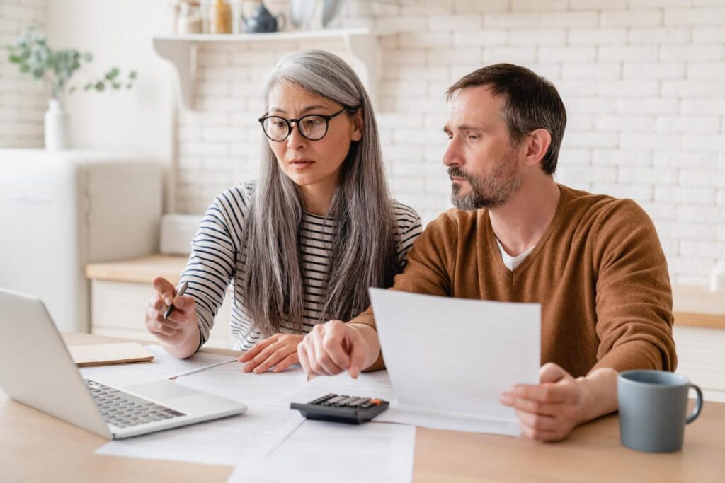 Couple reviewing bankruptcy exemptions paperwork with computer and calculator