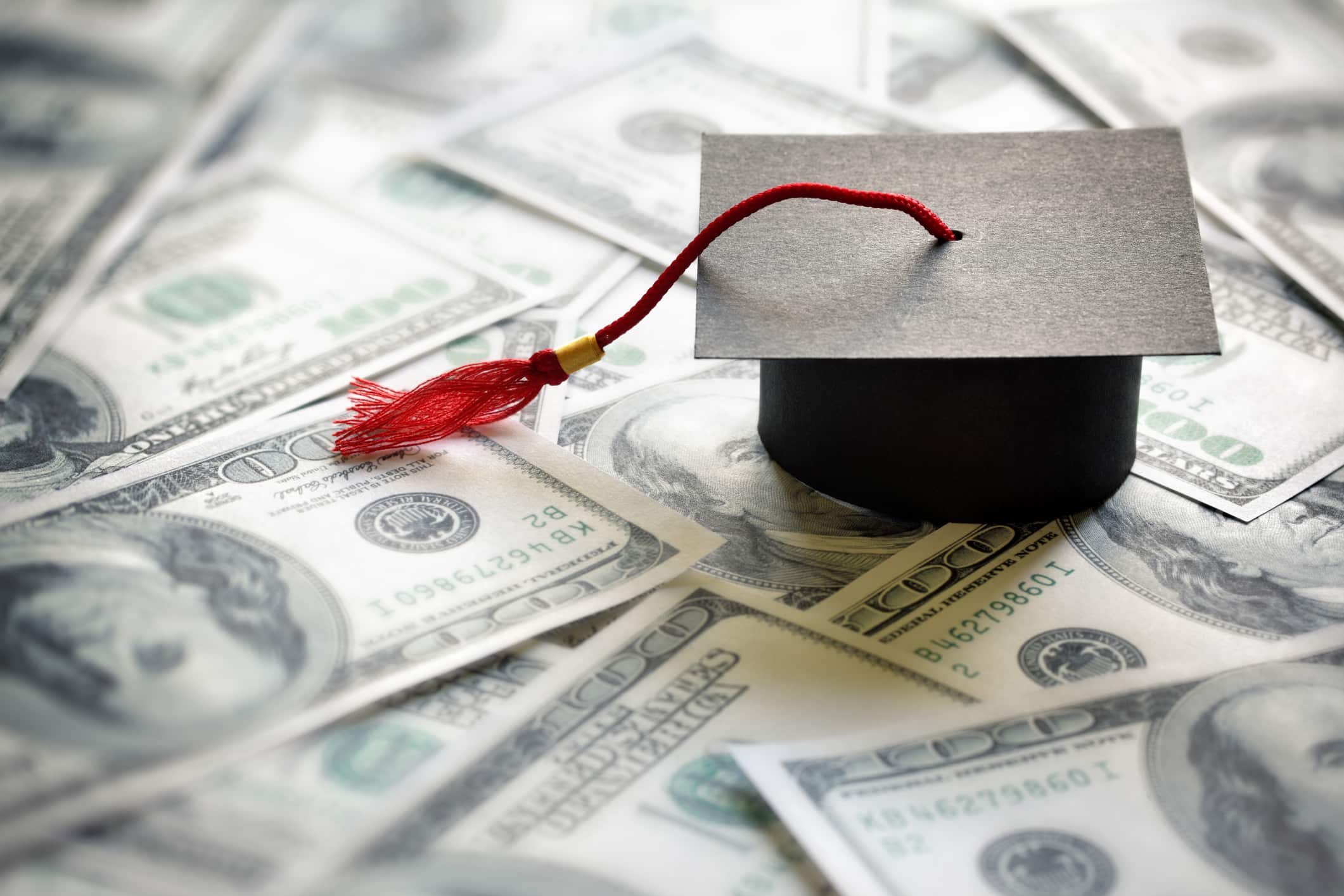 graduation cap on top of a pile of USD cash