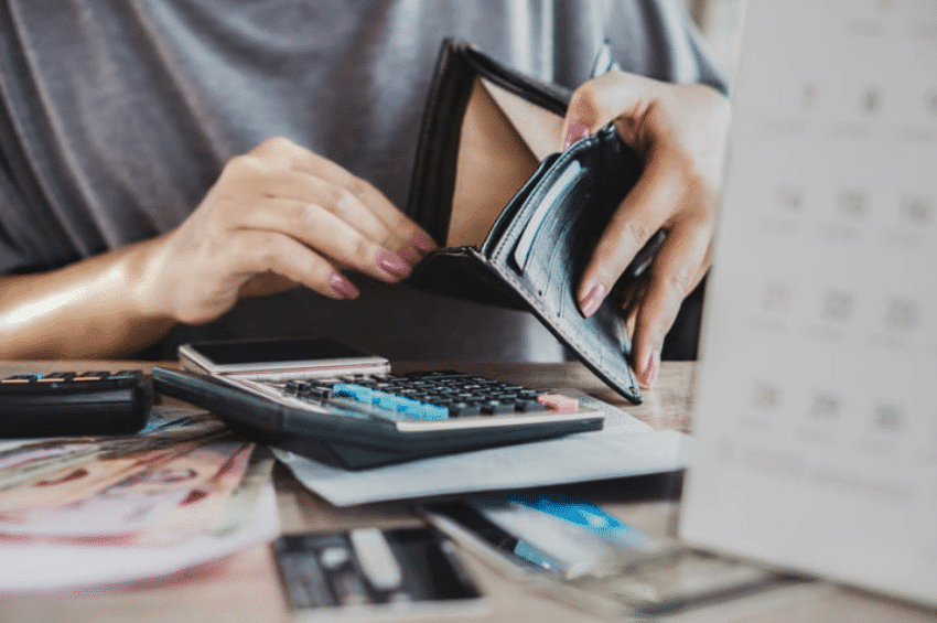 A woman's hand opens an empty wallet as she's looking for money for credit card debt